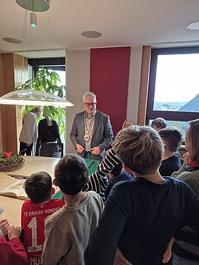 Viertklässler stehen während ihres Besuchs im Rathaus im Bürgermeisterzimmer und sehen sich das Goldene Buch und die Amtskette an