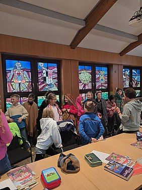 Schülerinnen und Schüler der Klasse 4a tragen Schaltücher des Oberfränkischen Textilmuseums entsprechend der Länder, in die die Produkte vertrieben wurden