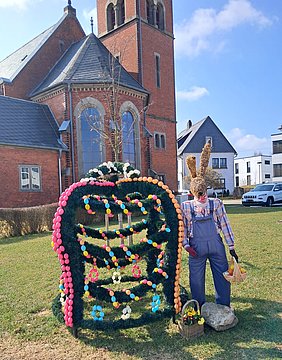Bunte Osterkrone mit Strohhasen vor der Kirche Wüstenselbitz