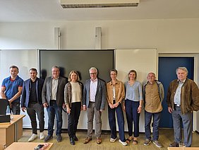 Besuch MdL Ursula Sowa in der Helmbrechtser Grund- und Mittelschule 9 Personen des Treffens, darunter Bürgermeister Pöhlmann und Landtagsabgeordnete Ursula Sowa stehen als Gruppe vor der Tafel im Klassenzimmer.