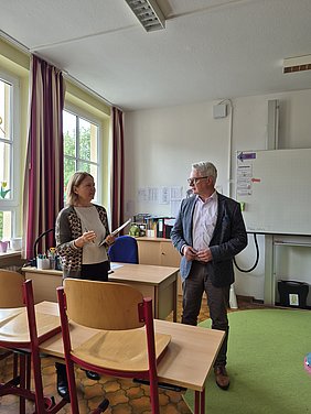 Austausch in einem der Grundschulklassenzimmer zwischen Ursula Sowa und Stefan Pöhlmann Landtagsabgeordnete Ursula Sowa und Bürgermeister Stefan Pöhlmann stehen in einem Klassenzimmer der Grundschule und tauschen sich zum Projekt aus.