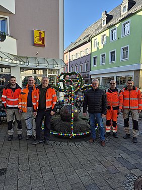 Bunte Osterkrone am Kugelbrunnen in der Helmbrechtser Innenstadt mit Baubetriebshofmitarbeitern und dem Bürgermeister