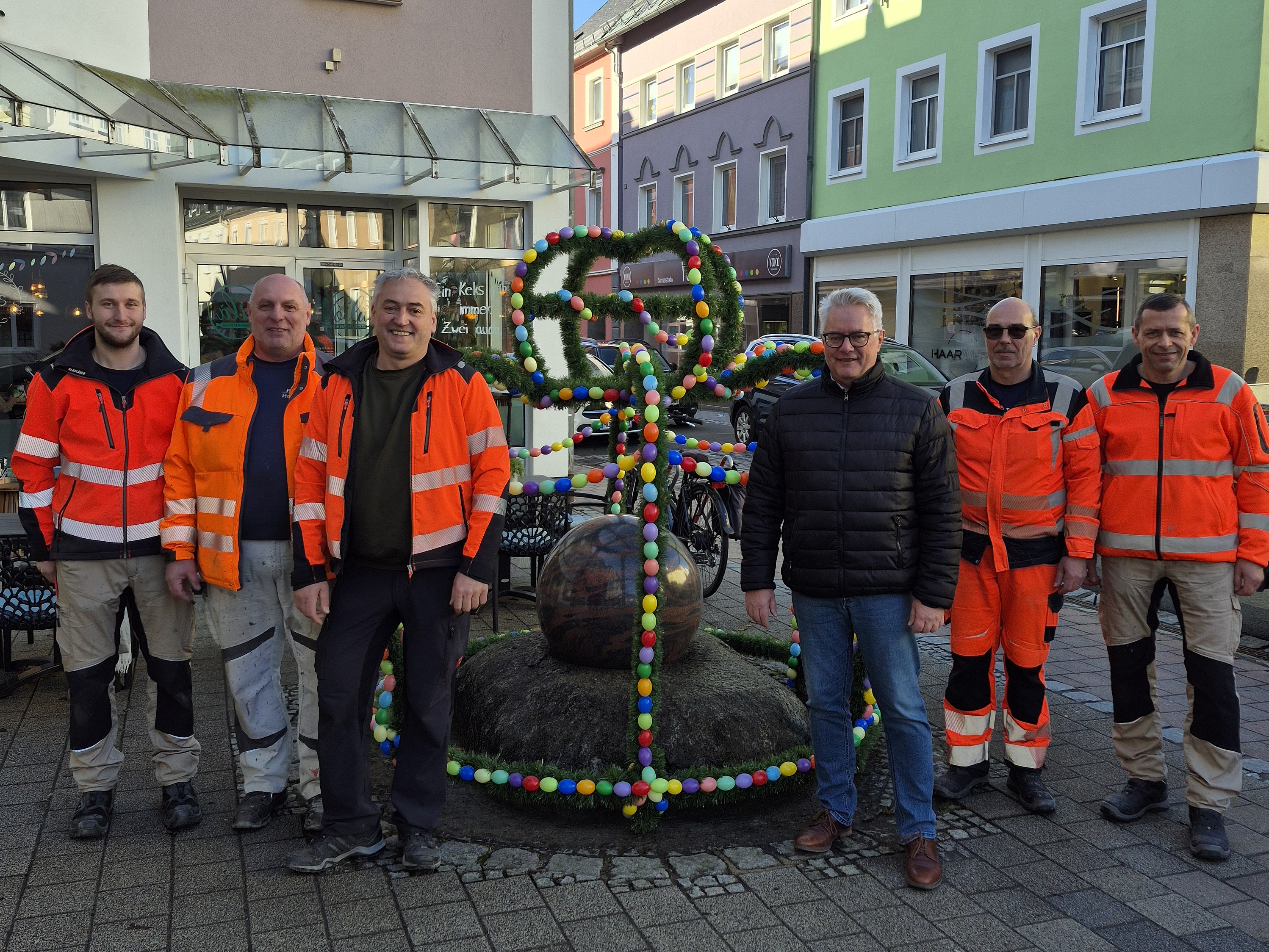 Bunte Osterkrone am Kugelbrunnen in der Helmbrechtser Innenstadt mit Baubetriebshofmitarbeitern und dem Bürgermeister