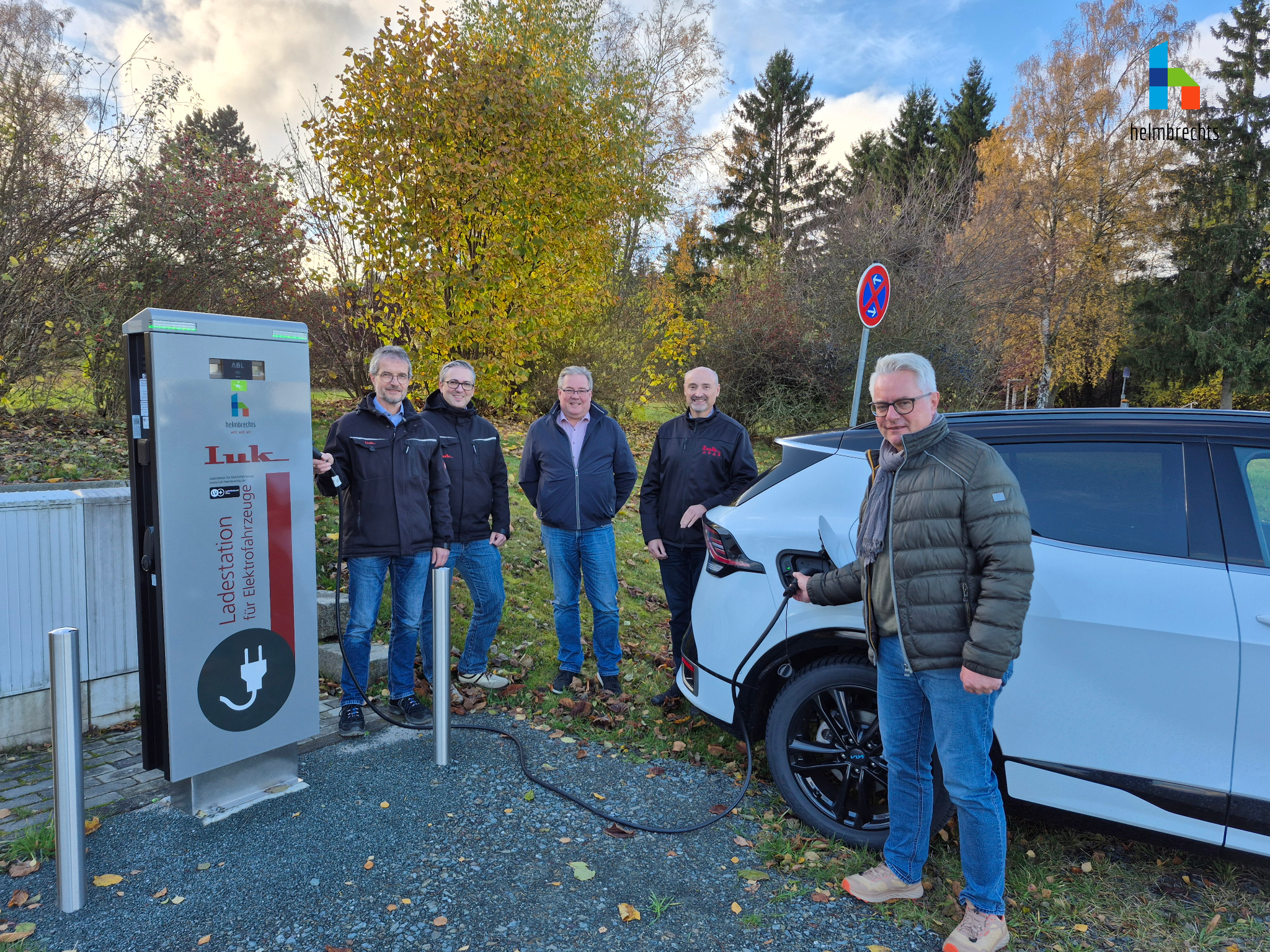 Einweihung der neuen E-Ladesäule in Wüstenselbitz Zwischen neuer Ladesäule und elektrischem PKW stehen die Geschäftsführer der Licht- und Kraftwerke Helmbrechts, der Elektromeister der LuK, der Bauamtsleiter der Stadt Helmbrechts sowie der Bürgermeister. Der Bürgermeister hält das Ladekabel, welches das Auto zur Ladesäule verbindet.