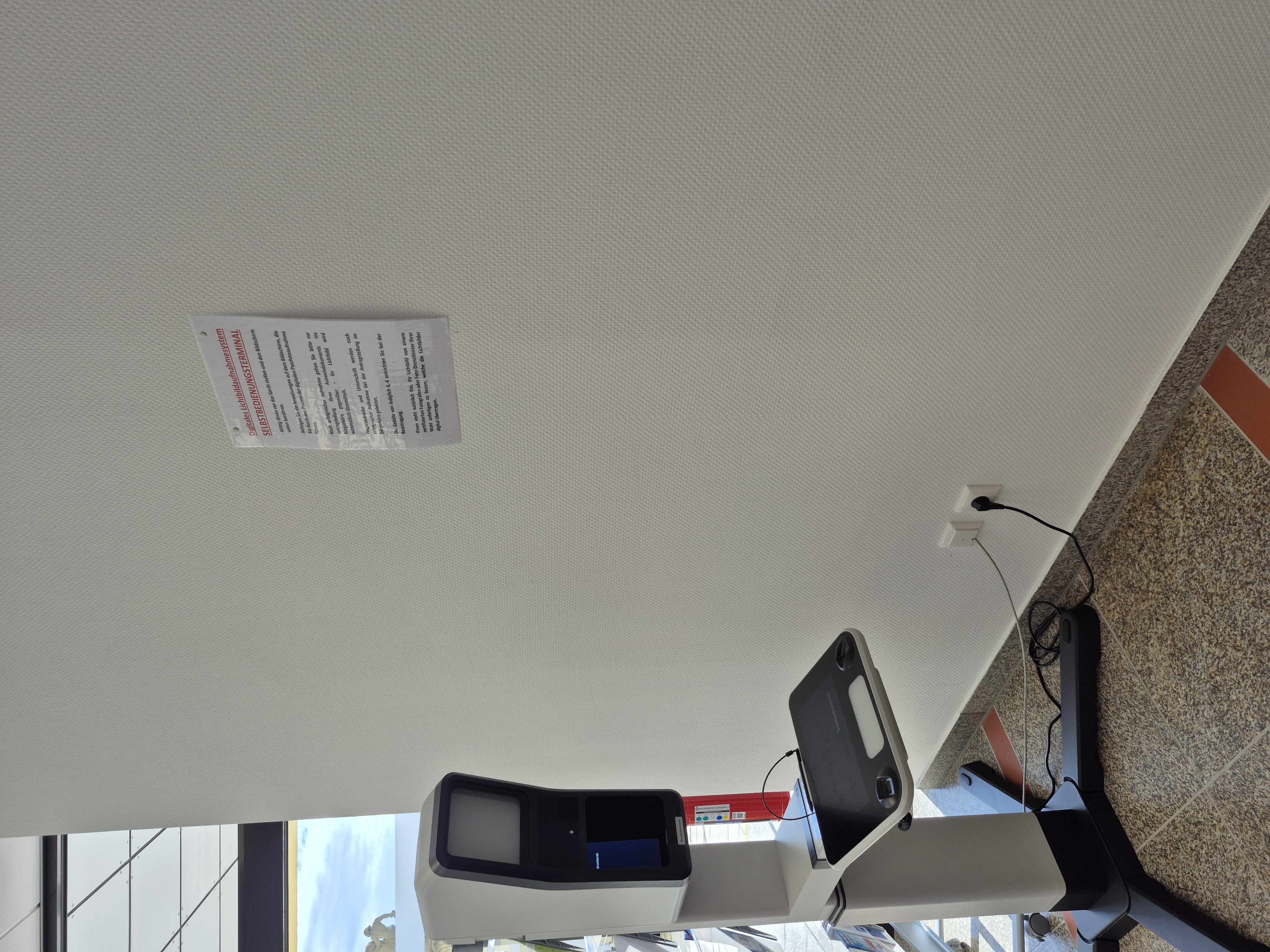 Das PointID® System steht vor der weißen Wand mit Anleitungszettel im Eingangsbereich vor dem Bürgerbüro im Helmbrechtser Rathaus.