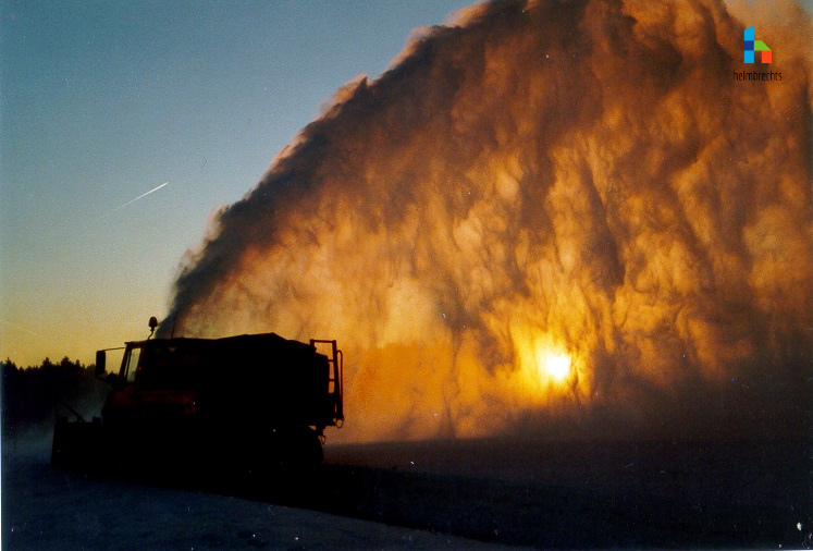 Winterdienstauto in den frühen Morgenstunden bei Sonnenaufgang beim Schnee fräsen