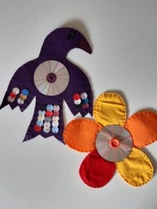 Zwei bunt, gebastelte Vogelschrecke. Einer in dunkelblau und in Form eines Vogels, ein anderer orange-rot und in Form einer Blume.
